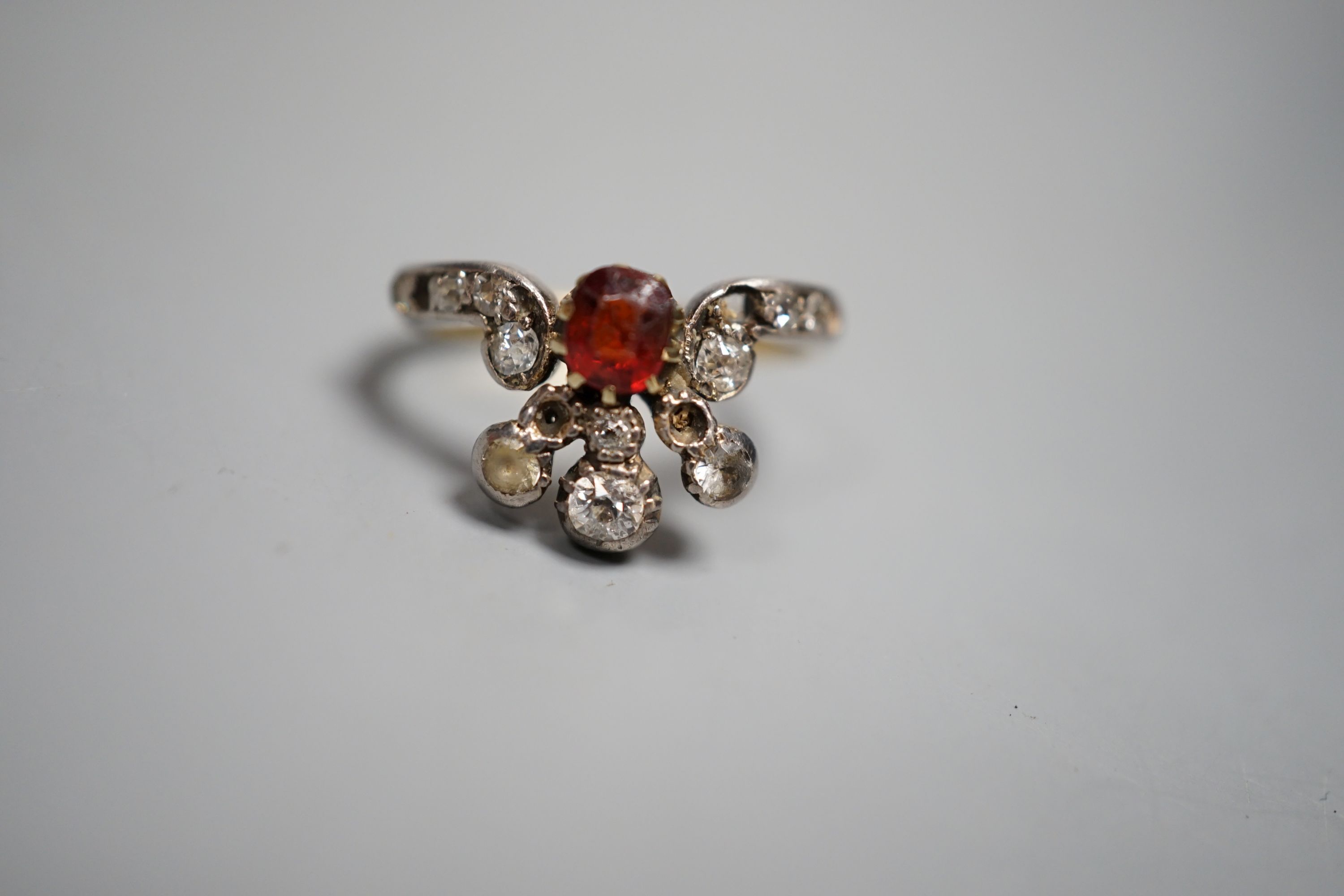 An early 20th century 18ct, garnet? and diamond cluster set dress ring(a.f.), with diamond set shoulders, size J. gross weight 3.5 grams.